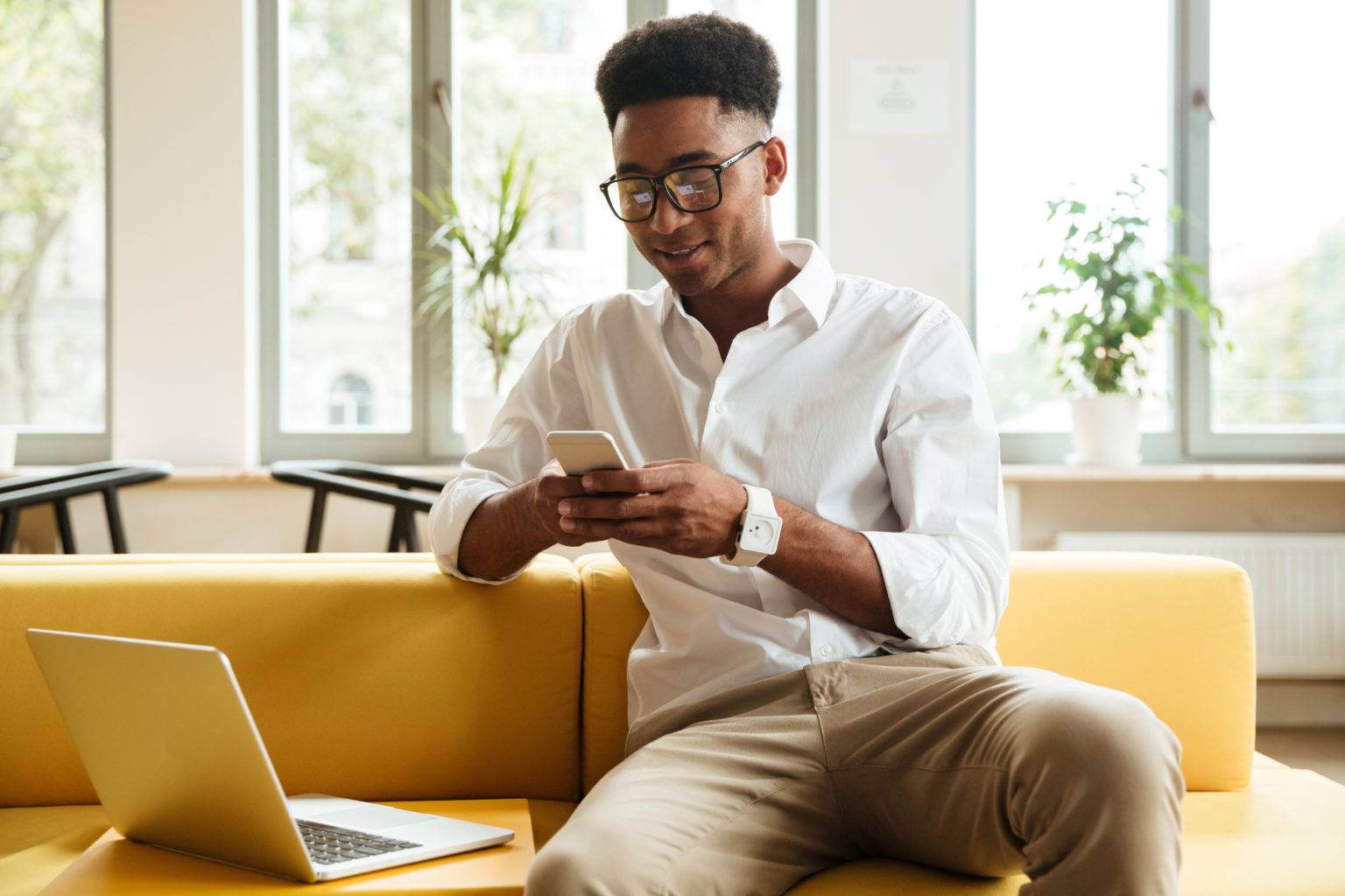 Smiling young african man sitting coworking chatting by phone.